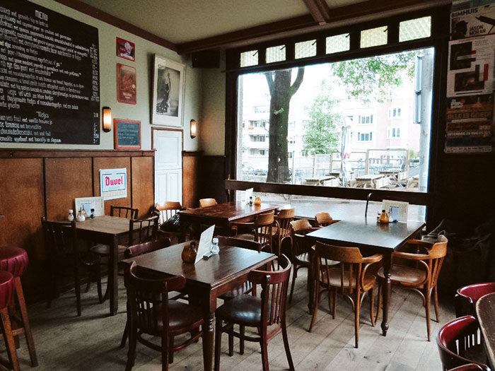 Houten tafels en stoelen in het warme interieur van Café Thuys